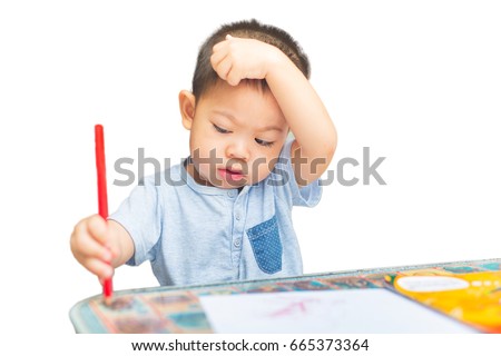 two years old boy is seriously drawing over white background.