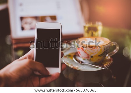 girl using smart phone in cafe. hand holding smart phone white screen.
