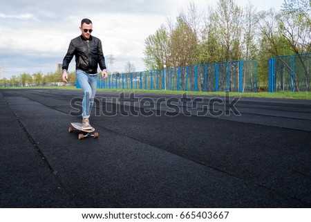 Man riding a skateboard on a sportsground, spring day, front view
