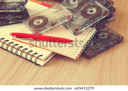 Notepads, pen and cassette tape on wooden table.