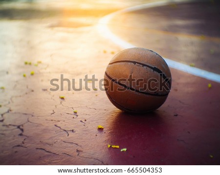 lonely basketball placed in the field during the evening time with the  sunlight through to fall into a reflection.