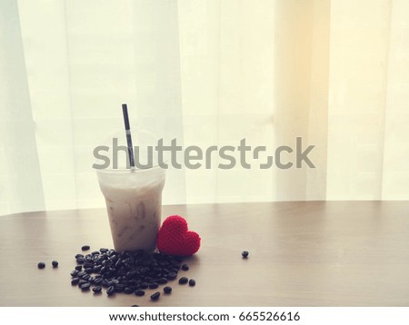 wood table with coffee cup of cappuccino, red heart shape sign and bean,concept of health care.