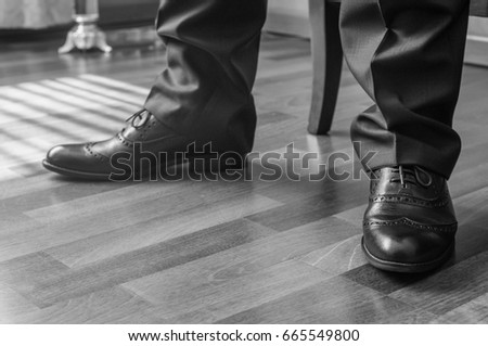 Black and white image of man standing wearing elegant shoes