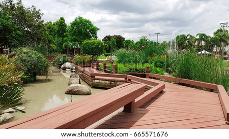 Brown wooden walk way with landscape of garden and pond