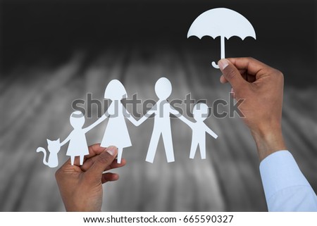hand holding an umbrella and a family in paper against wooden table