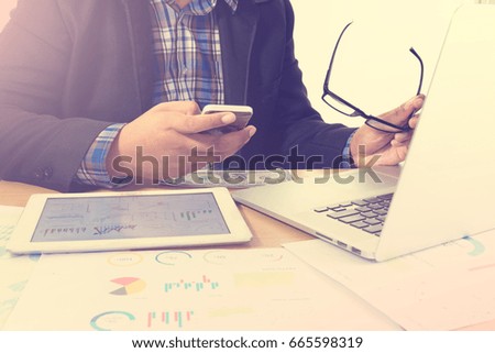 Business man making a phone call with smartphone working at office with laptop and documents on his desk,The manager for hard working on his plan project,vintage photo