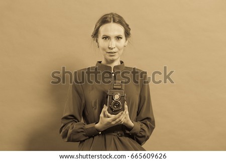 Woman retro style long dark gown taking picture with old camera, vintage photo