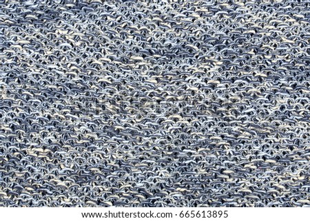 The texture of a knitted woolen fabric in dark blue, gray, yellow and white color. Natural background. 
