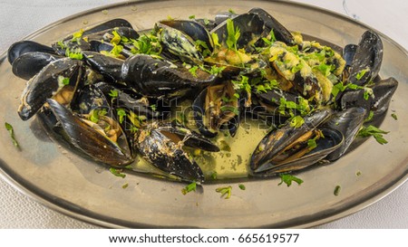 Seafood. Baked mussels on the traditional Greek recipe with cheese, parsley, garlic sauce with olive oil. Served in a metal plate - selective focus