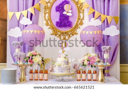 Interior decoration for a kids child birthday is one year in ultra violet trend year purple color. Candy, macaroon, tiered cake, and juices balloon. Anniversary dating one celebration. Royalty-Free Stock Photo #665621521