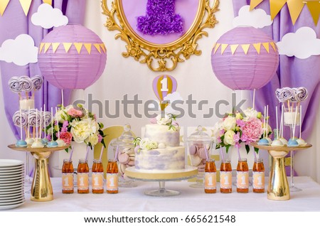 Interior decoration for a kids child birthday is one year in ultra violet trend year purple color. Candy, macaroon, tiered cake, and juices balloon. Anniversary dating one celebration. Royalty-Free Stock Photo #665621548