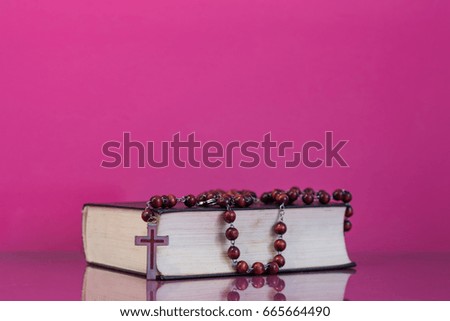 Bible and a crucifix on a pink table. Beautiful background.Religion concept.