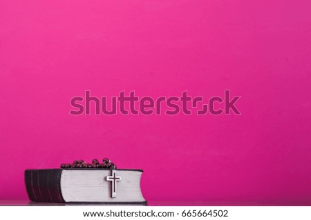 Bible and a crucifix on a pink table. Beautiful background.Religion concept.
