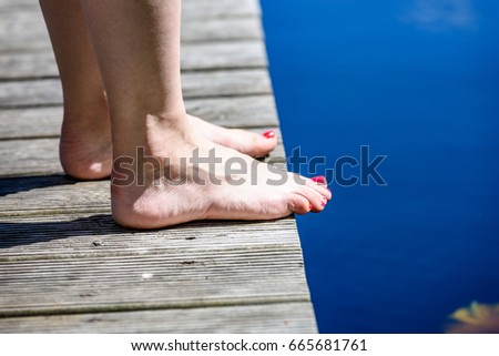 reflection of clouds in the lake with nice wooden boardwalk and womans legs with red fingernails