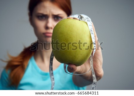 Woman diet, the problem of excess weight, a woman with an apple and with a centimeter in her hand