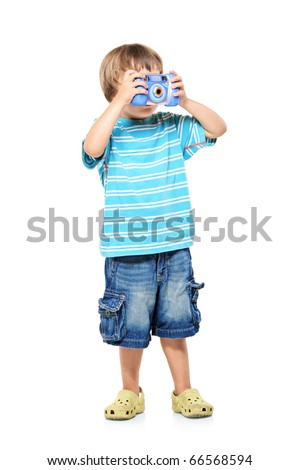 Full length portrait of a little boy taking pictures with a camera isolated against white background