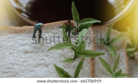 Miniature Greenhouse concept, group of miniature mini figures with planting tree on bread background