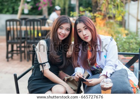 Asian girl with friend sitting talking in a coffee shop.