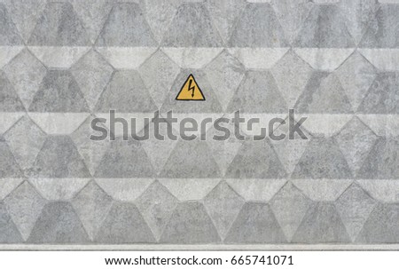 grey concrete wall with electrical hazard warning sign. yellow triangle with thunder