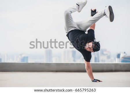 Bboy doing some stunts - Street artist breakdancing outdoors Royalty-Free Stock Photo #665795263