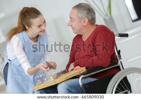 photo of happy elderly man with disability and helpful nurse