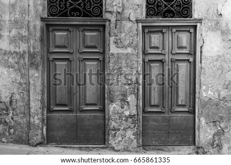 Building with traditional maltese doors in historical part of Valletta. Entrance to an abandoned house on the island of Malta. Black and white picture