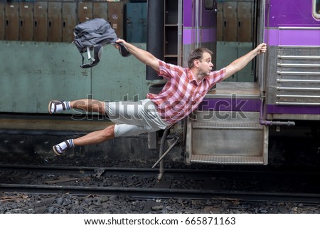 Man with backpack flies behind a moving train. Tourist holding a moving train from a railway station. Funny traveler catches the train in motion.Journey to the last minute. Royalty-Free Stock Photo #665871163