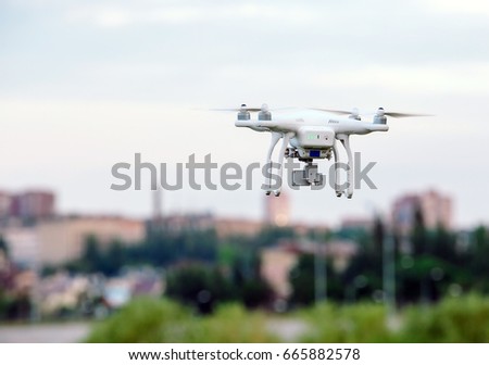 drone quad copter with high resolution digital camera flying hovering over the city
