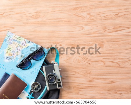Travel in Summer Concept Flat Lay or Top View Photo with Camera, Passport, Sunglasses, Map are prop on wooden background.