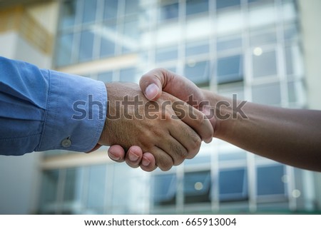 Businessmen is shaking hand in front of the building. Hope and milestones of business start here.