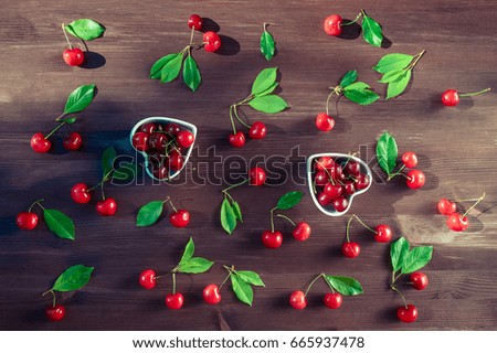  Basket with a cherry on a wooden table on a background of a green garden. View from above. Pattern of berries of sweet cherry and green foliage. Background of the berry