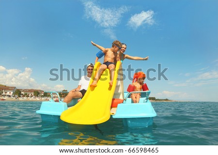 family with boy and girl on pedal boat with yellow slide in sea, view from water, shot from waterproof case Royalty-Free Stock Photo #66598465