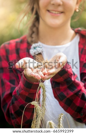 Portrait of teenage girl in checkered shirt posing in wheat field