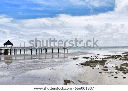  Sea view, bridge with little house lead to sea, sand beach with rocks, blue cloudy sky  