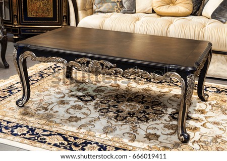 Classic vintage table in a furniture store. Luxurious wooden table with silver decoration. Beautiful brown table on a woolen carpet in a shop.