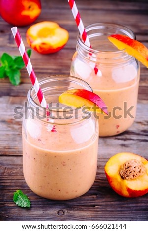 Healthy peach smoothies in a mason jar with mint on wooden rustic background