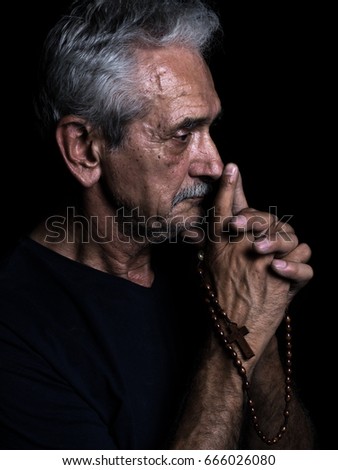 Old man praying with rosary in his hand