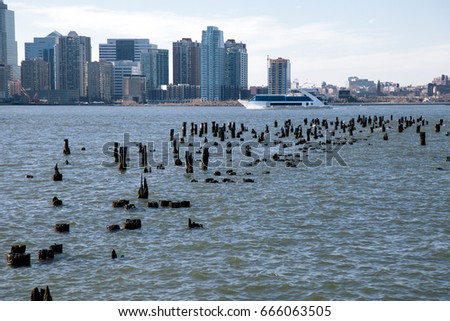 Wooden Logs peeking from the Hudson water surface, with New-Jersey's skyline in the background.