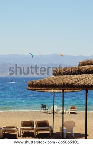 Photo of tropical sea and beach chairs under umbrellas. Summer travel and vacation concept