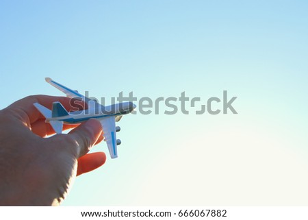close up photo of man's hand holding toy airplane against blue sky