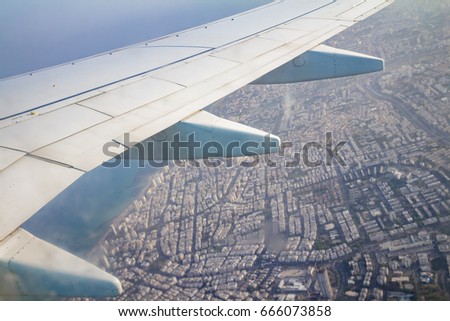Airplane wing on the sky and over land with building of Tel Aviv city and the Mediterranean sea.