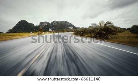 Motion blurred asphalt road and mountains on a horizon