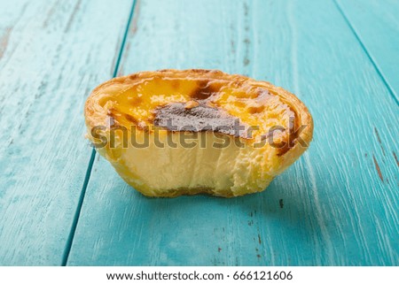 studio shoot of portuguese egg tart with a bite on a wood background