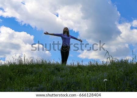 Silhouette young woman open arms on hill