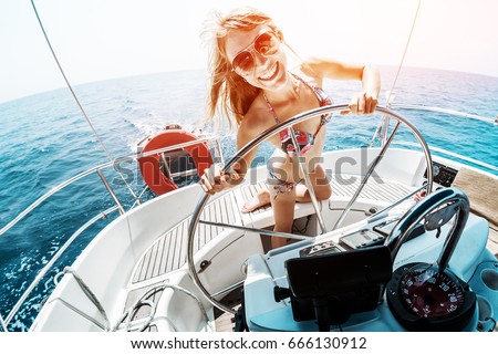 Young woman in bikini steering the sailing boat in a tropical sea