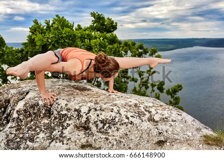 Young woman doing yoga fitness exercises outdoor in river landscape.