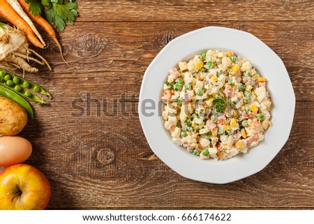 Traditional salad with cooked vegetables with mayonnaise. Wooden background. Top view.