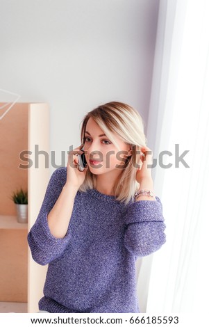 Beautiful young woman talking on the mobile phone at home