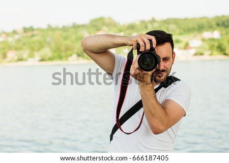 Young man photographer taking pictures with his DSLR