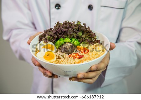 Chef holding thai noodle (Asian ramen) with eggs and mushroom and vegetable and tofu in a bowl